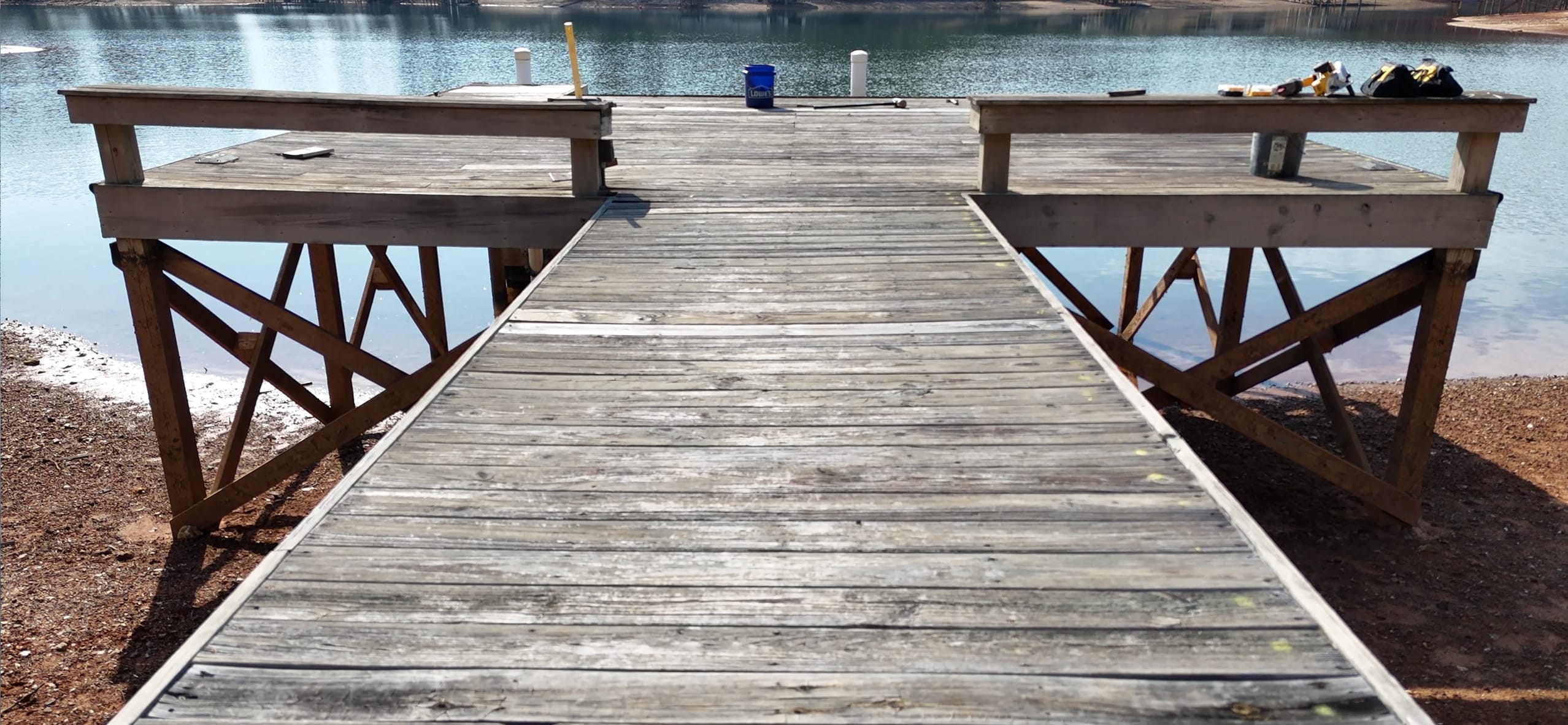 Weathered gray wood dock with worn decking and rotted supports on Lake Martin in Equality, Alabama, before repair and re-decking, during winter drawdown
